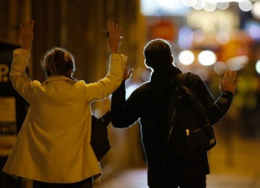 Dua warga berjalan ke arah polisi dengan tangan terangkat, menunjukkan tangan, setelah terjadi peristiwa penembakan. (Foto: Reuters/BBC News)