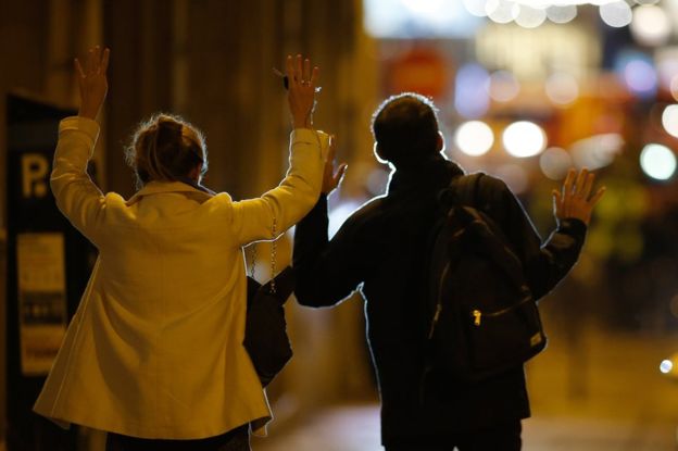 Dua warga berjalan ke arah polisi dengan tangan terangkat, menunjukkan tangan, setelah terjadi peristiwa penembakan. (Foto: Reuters/BBC News)