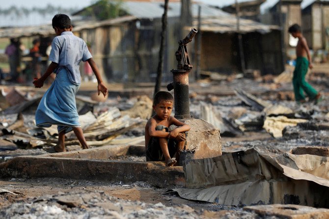 Seorang bocah laki-laki (duduk) dan lainya berjalan di area yang terbakar, setelah kebakaran menghancurkan tempat penampungan di sebuah kamp pengungsi Muslim Rohing, di sebelah barat Negara Bagian Rakhine dekat Sittwe, Myanmar, 3 Mei 2016. (Foto: Reuters/Arab News)