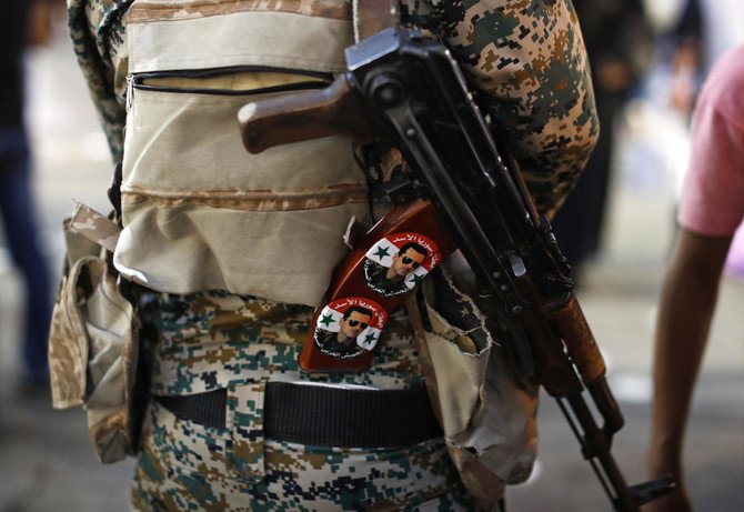 Seorang tentara Suriah memegang senapan AK-47 yang ditempeli stiker Presiden Bashar Assad bertuliskan bahasa Arab yang berbunyi, "Pahlawan Suriah Assad," di pos pemeriksaan di pasar Hamadiyah, di Kota Tua dari Damaskus, Suriah. Foto ini diabadikan 19 Juli 2018. (Foto: Dokumentasi AP/Arab News)