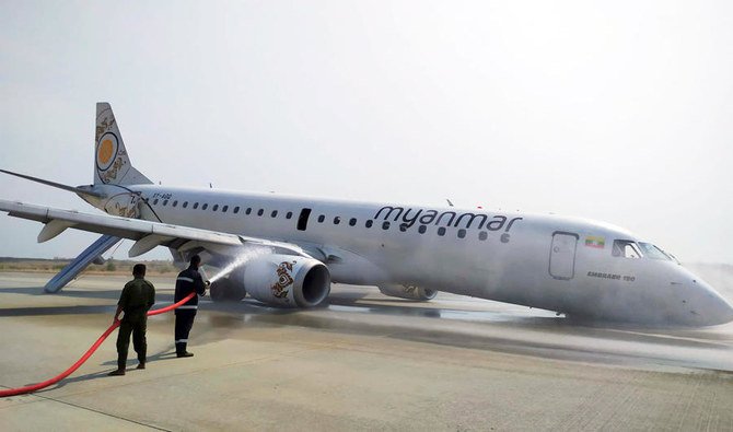 Petugas pemadam kebakaran melakukan penyemprotan pemadam untuk mengamankan pesawat Myanmar National Airline (MNA), yang mengalami kecelakaan di bandara Internasional Mandalay, Myanmar, Minggu (12/5). (Foto: AP/Arab News)