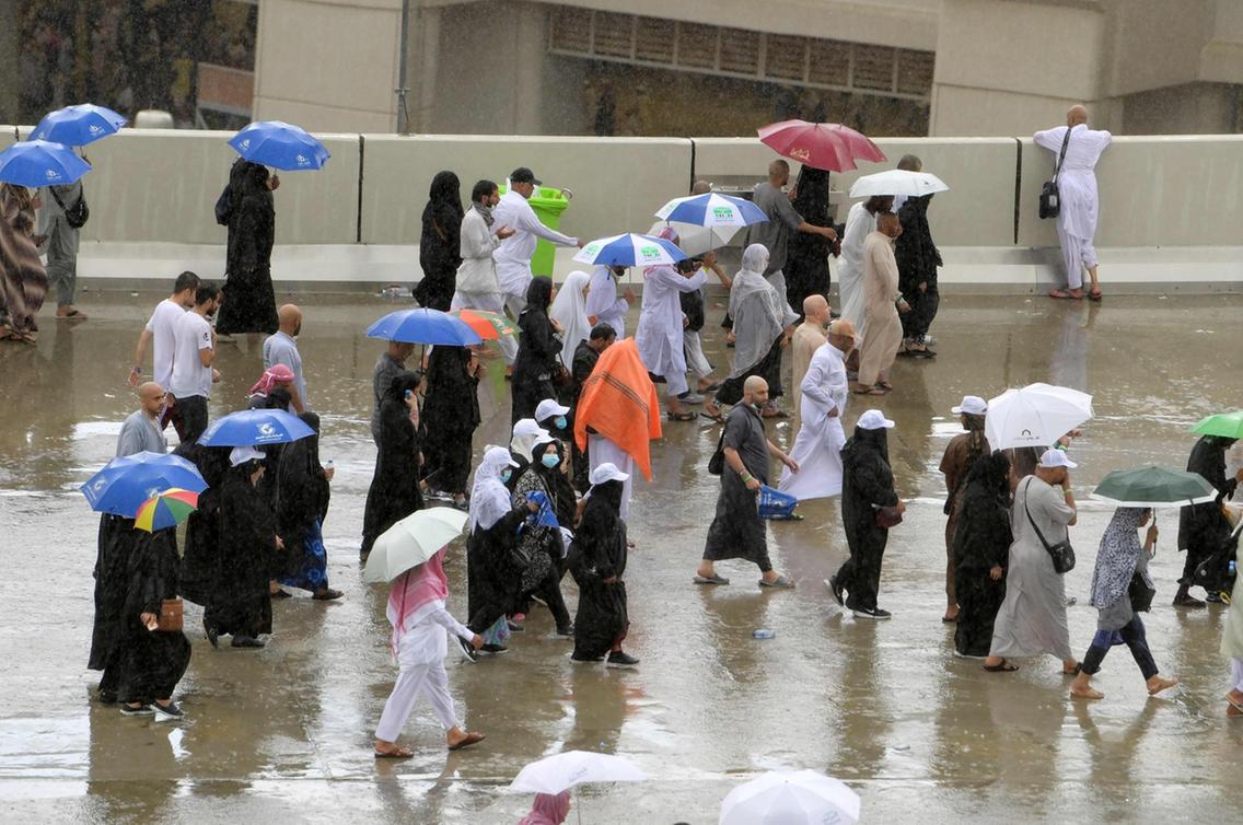 Hujan menguyrur umat Muslim saat menjalani ritual melempar jumrah, Senin (12/8) di Mina. (Foto: AFP/The National)