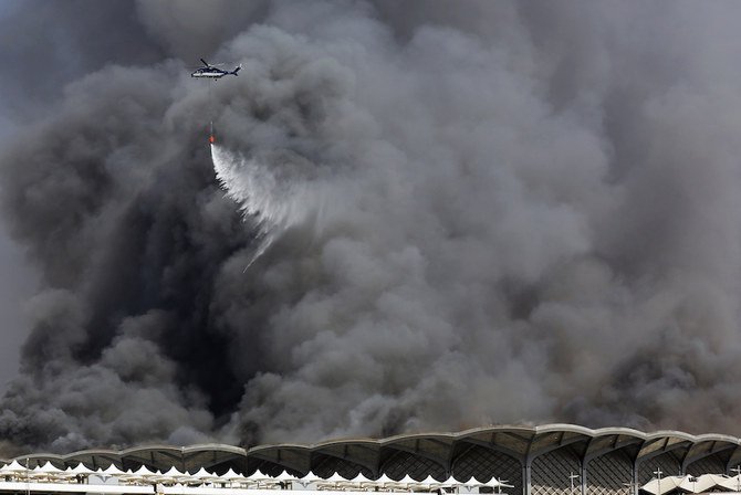 Helikopter pemadam kebakaran menyemprotkan air ke kobaran api di stasiun Haramain di Jeddah. (Foto: AP/Arab News)