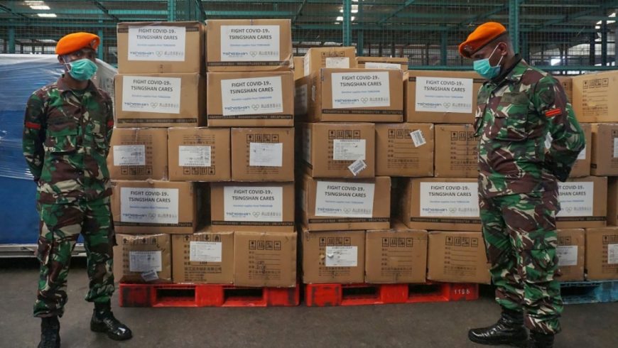 Tentara Indonesia berjaga-jaga di sebelah kotak-kotak peralatan medis dan bantuan yang tiba dari China pada Jumat (27/3) pagi.( Foto: AFP/Al Jazeera)