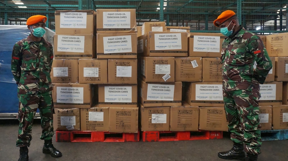 Tentara Indonesia berjaga-jaga di sebelah kotak-kotak peralatan medis dan bantuan yang tiba dari China pada Jumat (27/3) pagi.( Foto: AFP/Al Jazeera)