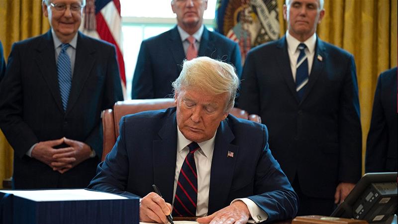 Presiden Amerika Serikat Donald Trump menandatangani Undang-Undang Bantuan Korona, Bantuan, dan Keamanan Ekonomi (CARES), paket penyelamatan $ 2,2 triliun untuk memberikan bantuan ekonomi di tengah wabah koronavirus. (Fotto: AFP/Al Jazeera)