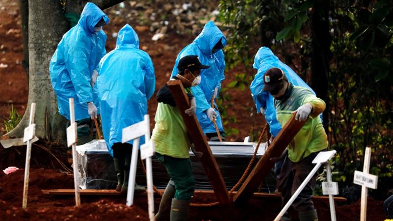 Pekerja kota mengenakan jas hujan sebagai alat pelindung saat mengubur korban COVID-19 di pemakaman di Jakarta, Indonesia, baru-baru ini.(Foto: Reuter/Al Jazeera)