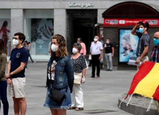 Orang-orang dengan menggunaan masker berdiri ‘selama satu menit’ setiap hari untuk mengenang para korban virus korona di Madrid. (Foto: Reuters/Al Jazeera)