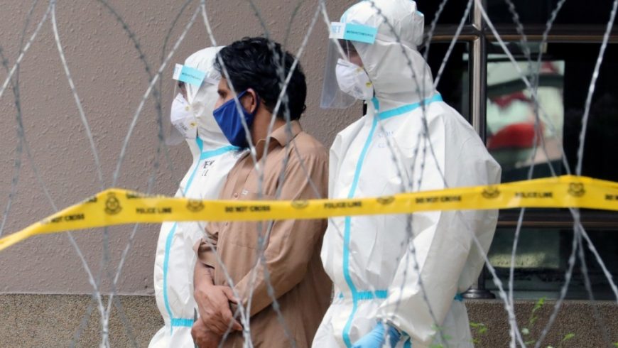 Petugas polisi yang mengenakan pakaian pelindung menjemput seorang pekerja migran dari sebuah apartemen di bawah “penguncian” yang ditingkatkan di pusat kota di Kuala Lumpur, Jumat lalu. (Foto: Reuters/Al Jazeera)