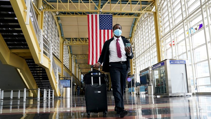 Seorang penumpang berjalan di Bandara Nasional Reagan di Washington, DC. Pihak Airlines menyatakan, penumpang bisa dilarang jika mereka menolak untuk memakai masker wajah. (Foto: Reuters/Al Jazeera)