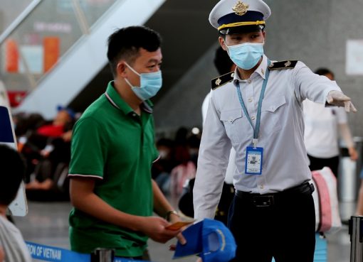 Seorang anggota staf dari Pusat Pengendalian Penyakit Vietnam membantu penumpang di bandara internasional Danang pada 27 Juli 2020. (Foto AFP/Al Jazeera)