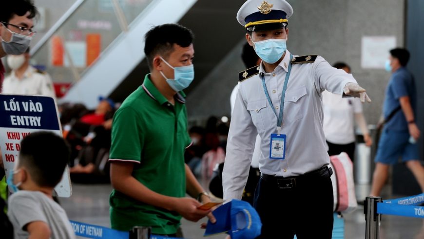 Seorang anggota staf dari Pusat Pengendalian Penyakit Vietnam membantu penumpang di bandara internasional Danang pada 27 Juli 2020. (Foto AFP/Al Jazeera)