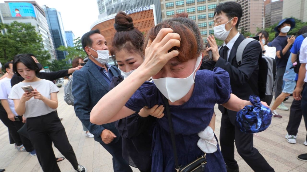 Pelayat, banyak yang memakai topeng, berkumpul di luar Balai Kota Seoul pada hari Sabtu untuk menyampaikan rasa berkabung bagi almarhum Walikota Seoul Park Won, di tengah penyebaran virus corona di kota itu. (Foto AP/ Al Jazeera)