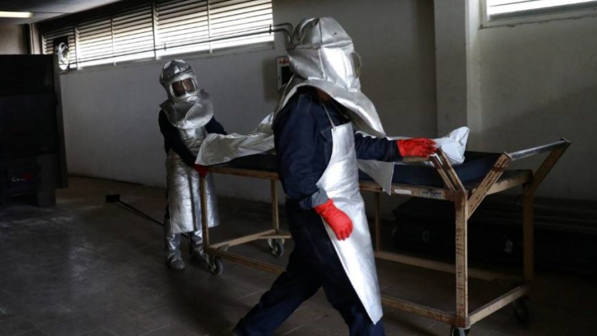 Para pekerja mengurusi kantung mayat yang berisi mayat seorang korban COVID-19 di sebuah krematorium di Mexico City pada hari Minggu. (Foto Reuters/Al Jazeera)