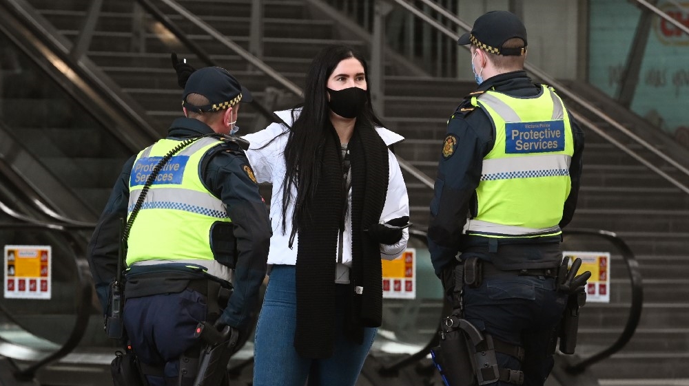 Petugas layanan perlindungan berbicara dengan seorang wanita di Stasiun Southern Cross, di Melbourne pada 7 Agustus 2020, saat kota tersebut dikunci secara ketat. (Foto AFP/ Al Jazeera)