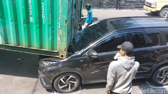 Truk membawa kontainer tersangkut jembatan terjadi di Kota Bogor, Jabar. Kontainer yang dibawa truk tersebut meniban mobil yang melaju di belakangnya.