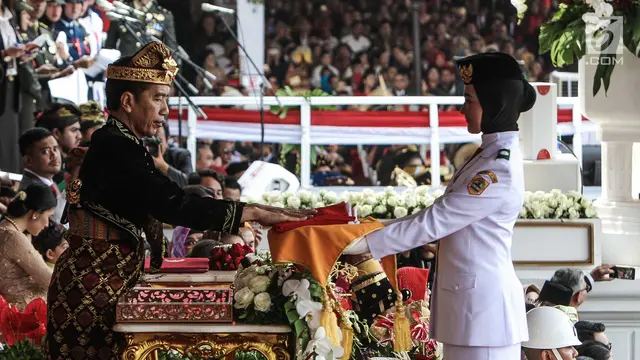 Presiden Joko Widodo menyerahkan duplikat bendera pusaka kepada Paskibraka Salma El Mutafaqqiha dalam Upacara Peringatan Detik-Detik Proklamasi Kemerdekaan Indonesia ke-74 Tahun 2019 di Istana Merdeka, Jakarta, Sabtu (17/8/2019).